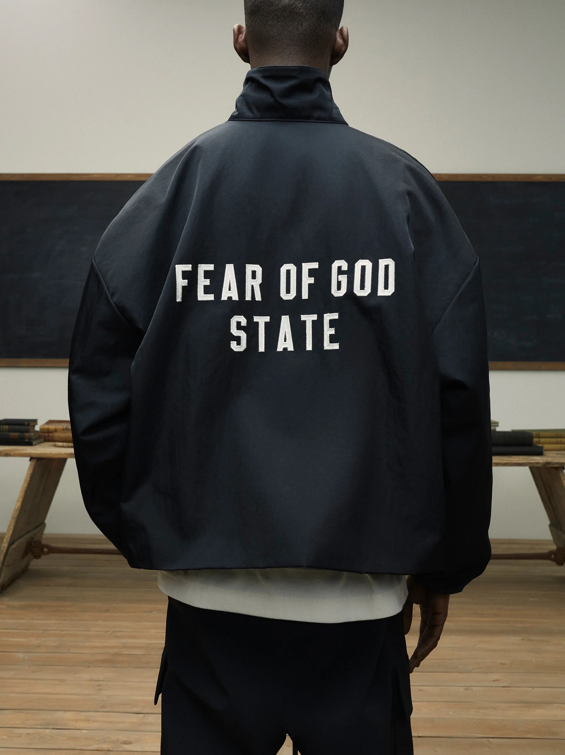FEAR OF GOD ESSENTIALS 24FW stand collar windbreaker with appliqué letter embroidery.